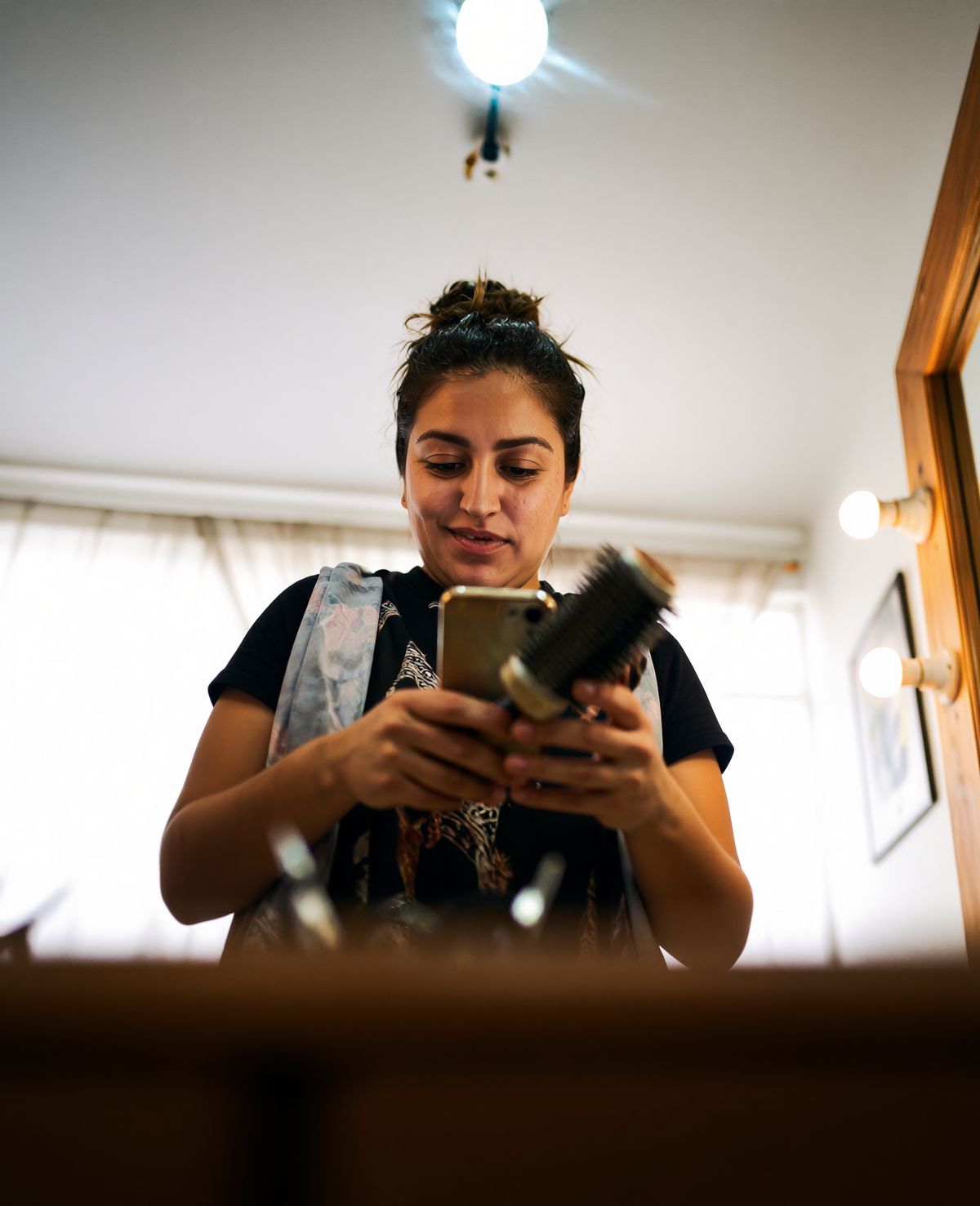 Estilista con su celular y un cepillo en la mano